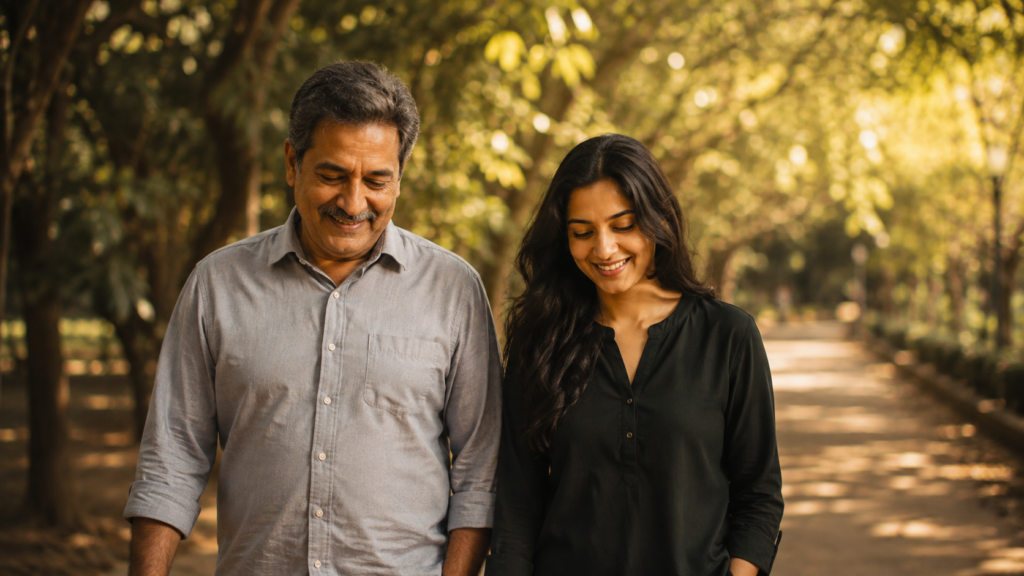 A father and daughter walking together on a quiet park path in warm afternoon light
